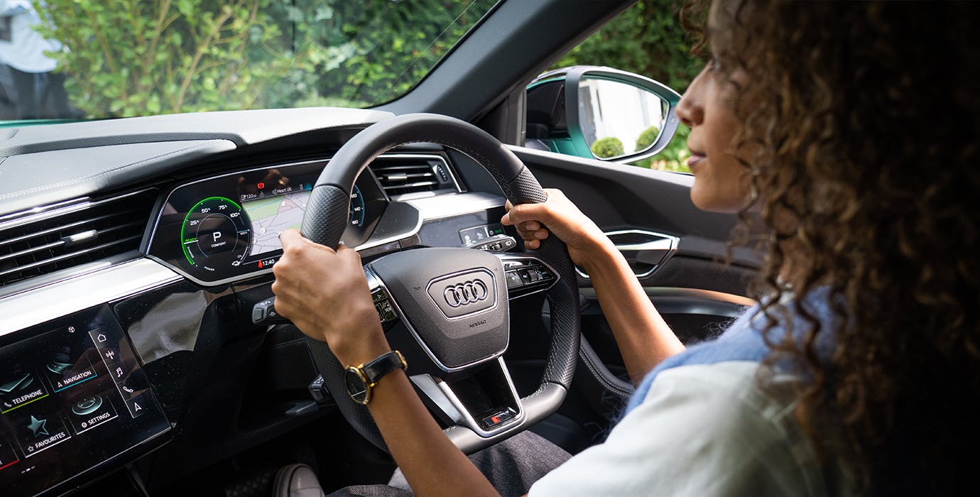 Woman sitting in the driver's seat, driving an Audi e-tron