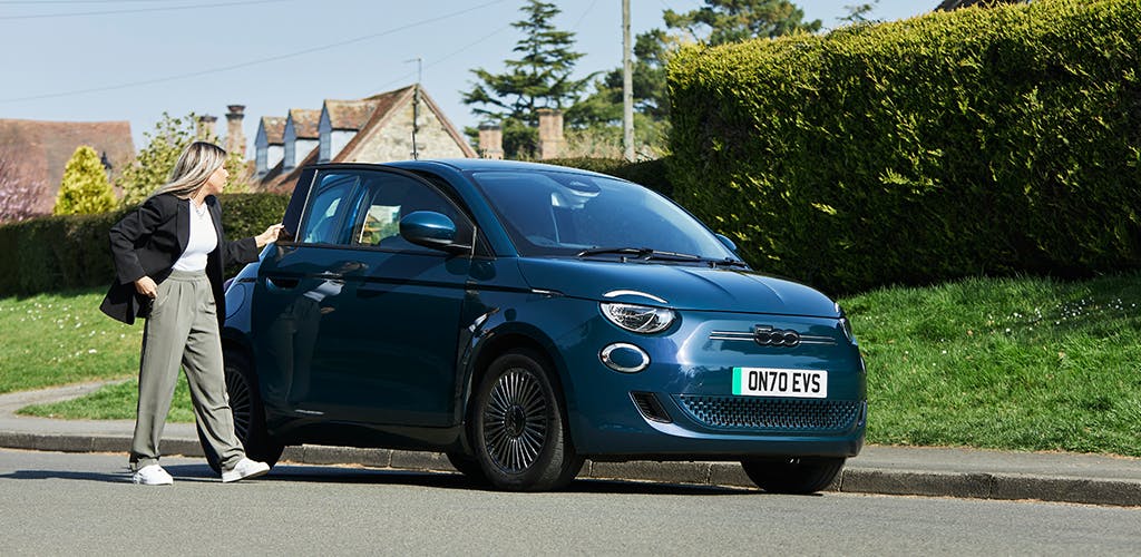 Woman opening the driver's door of a Fiat 500 hatchback 