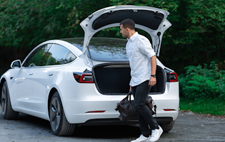 Man taking a bag out of the boot of a white Tesla Model 3