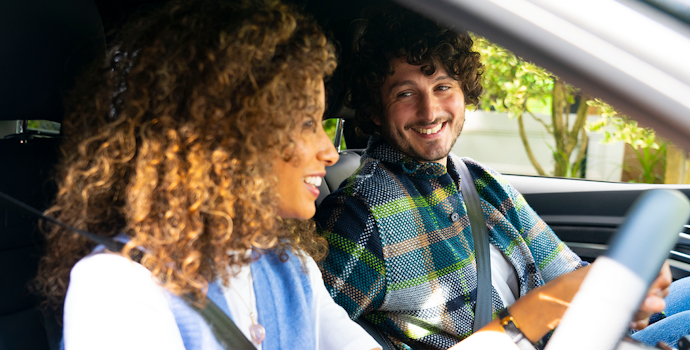 A man and woman are smiling and sitting in the front seats of an Audi e-tron