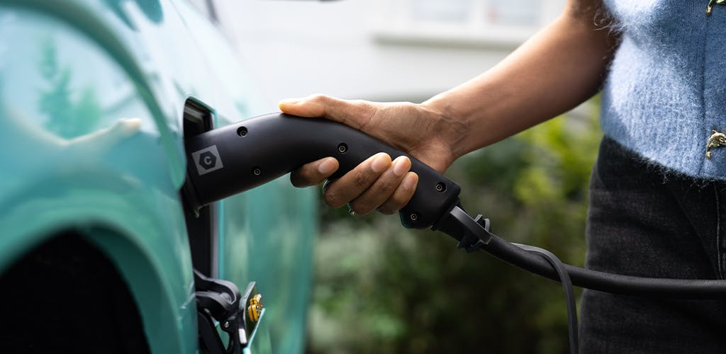 Hand placing electric car charger into a green Audi e-tron