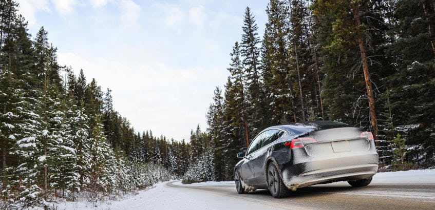 Tesla electric car driving on a snowy road