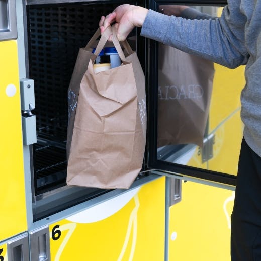 Person removes grocery bag from yellow parcel locker