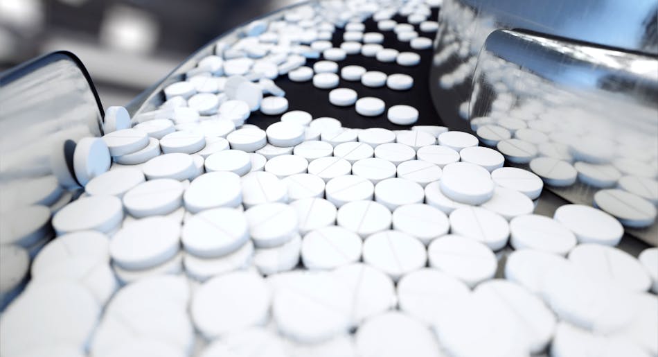 White medicine pills coming out of a machine in a pharma factory.