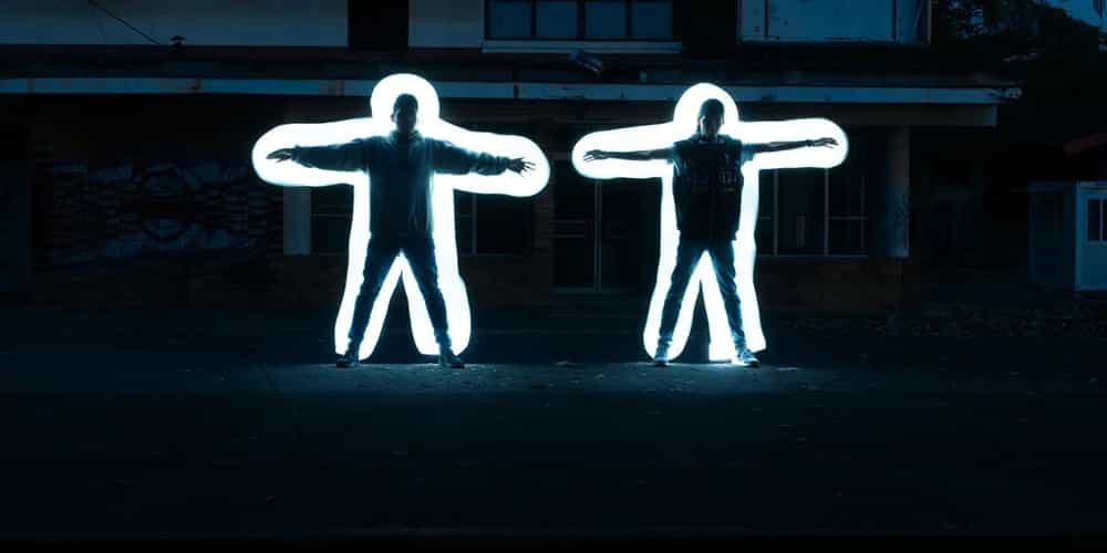 Arkalarındaki ışıklandırma ile poz veren iki kişi