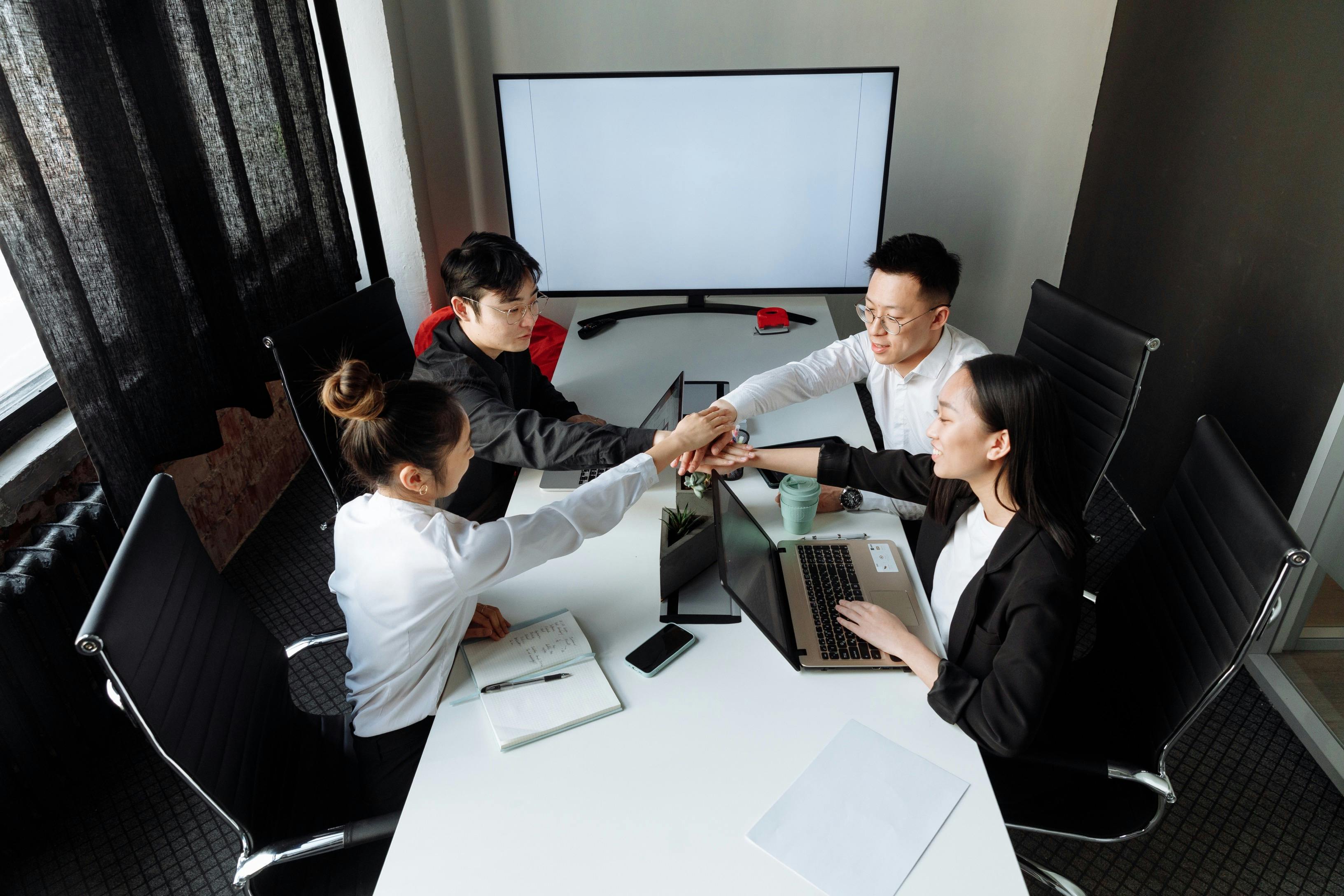 Business team joining hands together during meeting in conference room