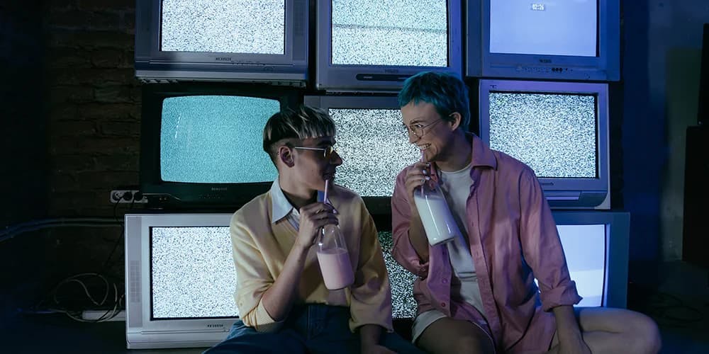 Televizyonlar önünde içecek içerek oturan iki kişi