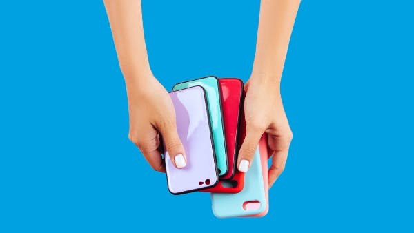 Hands holding multiple colorful phone cases on blue background