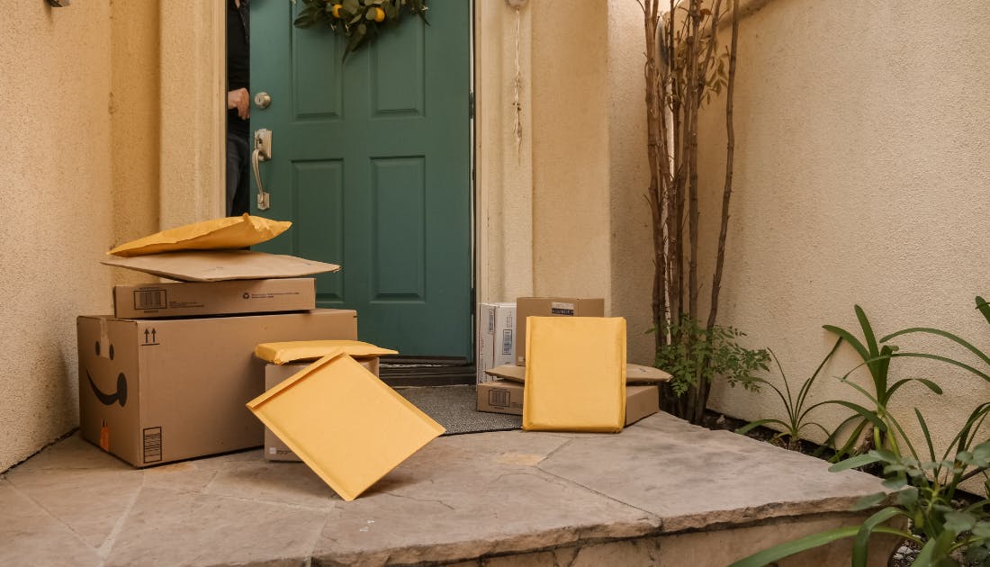 Packages and envelopes delivered at front doorstep with green door