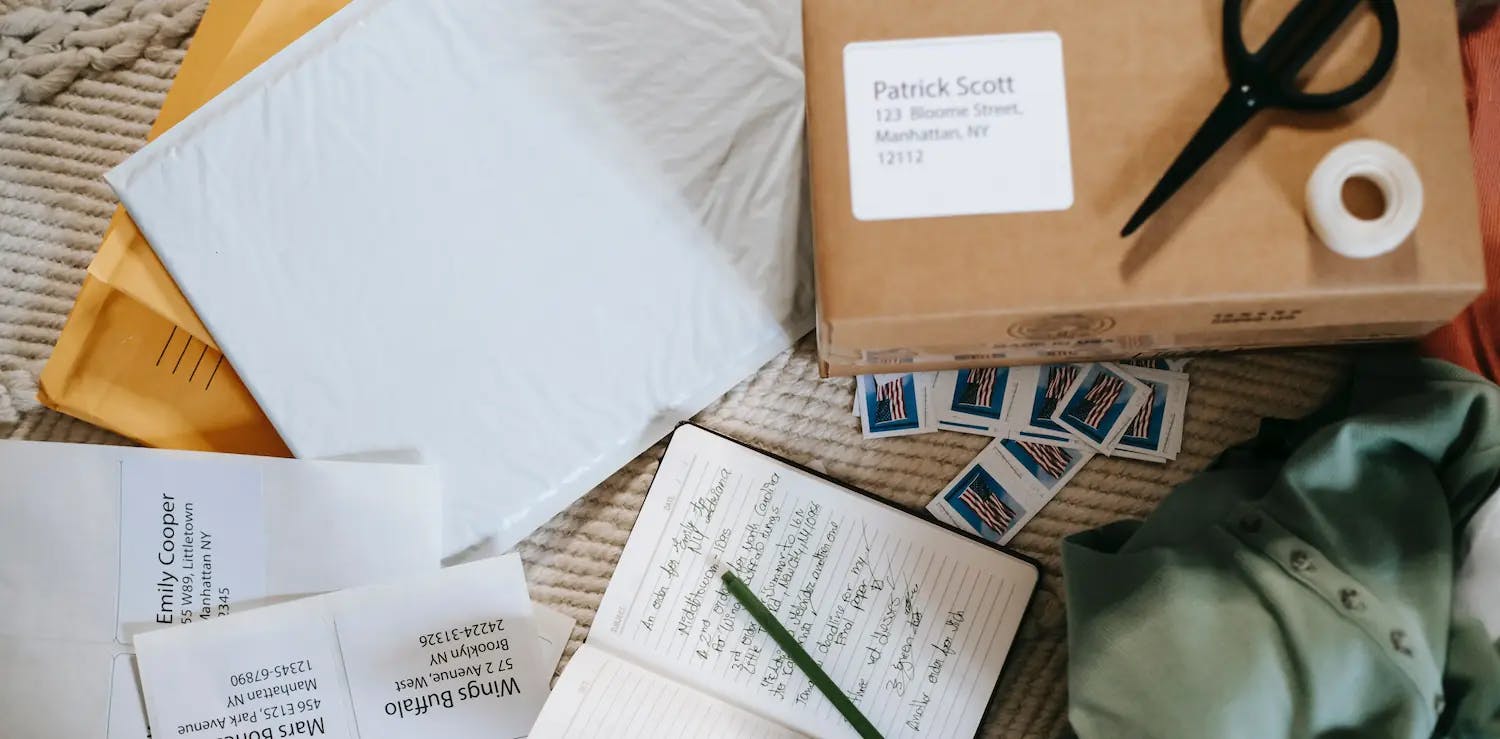 Office supplies including a notebook, pen, scissors, envelopes, and various addresses