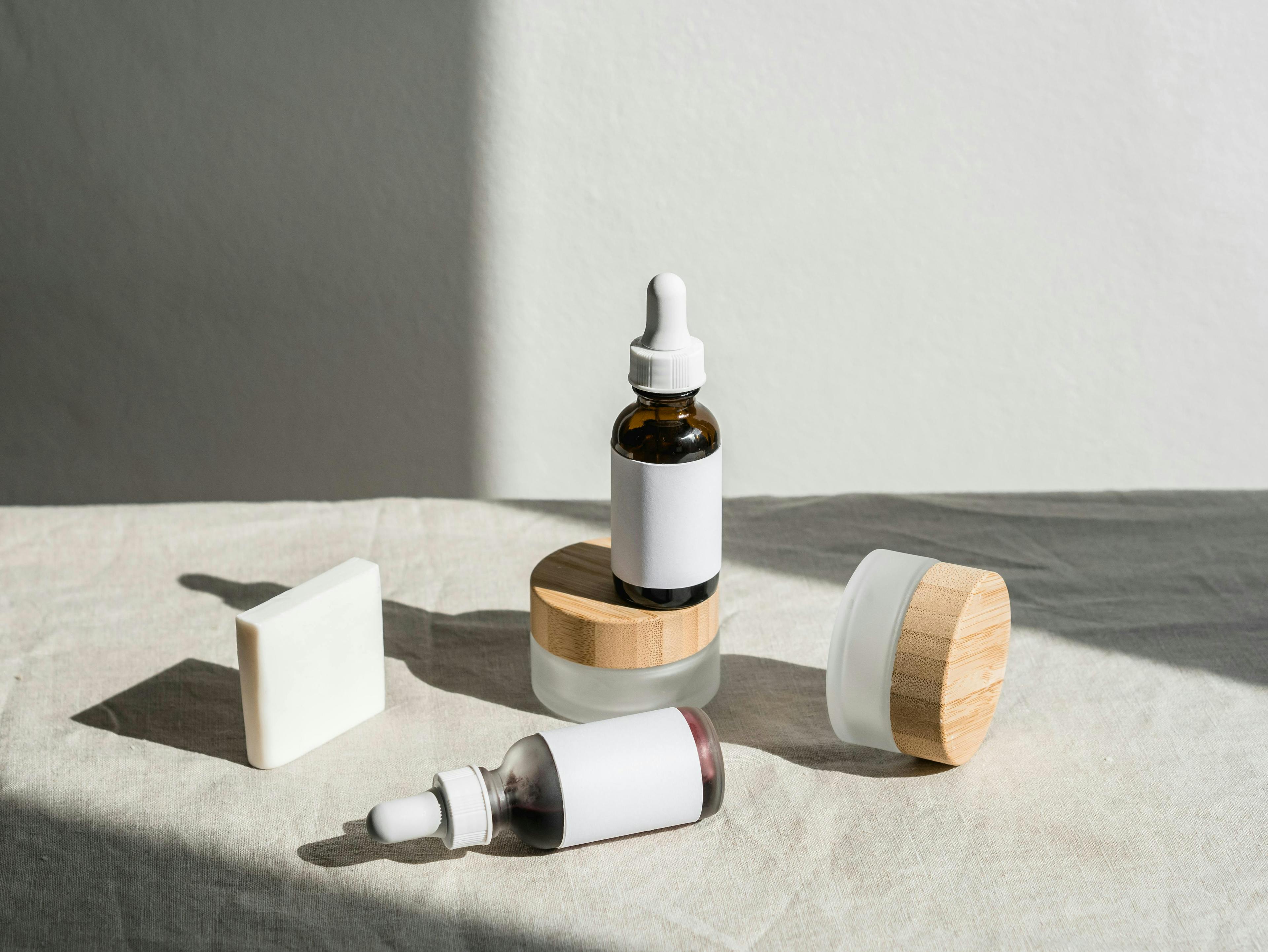 Minimalist skincare products with dropper bottles and wooden lids on linen fabric