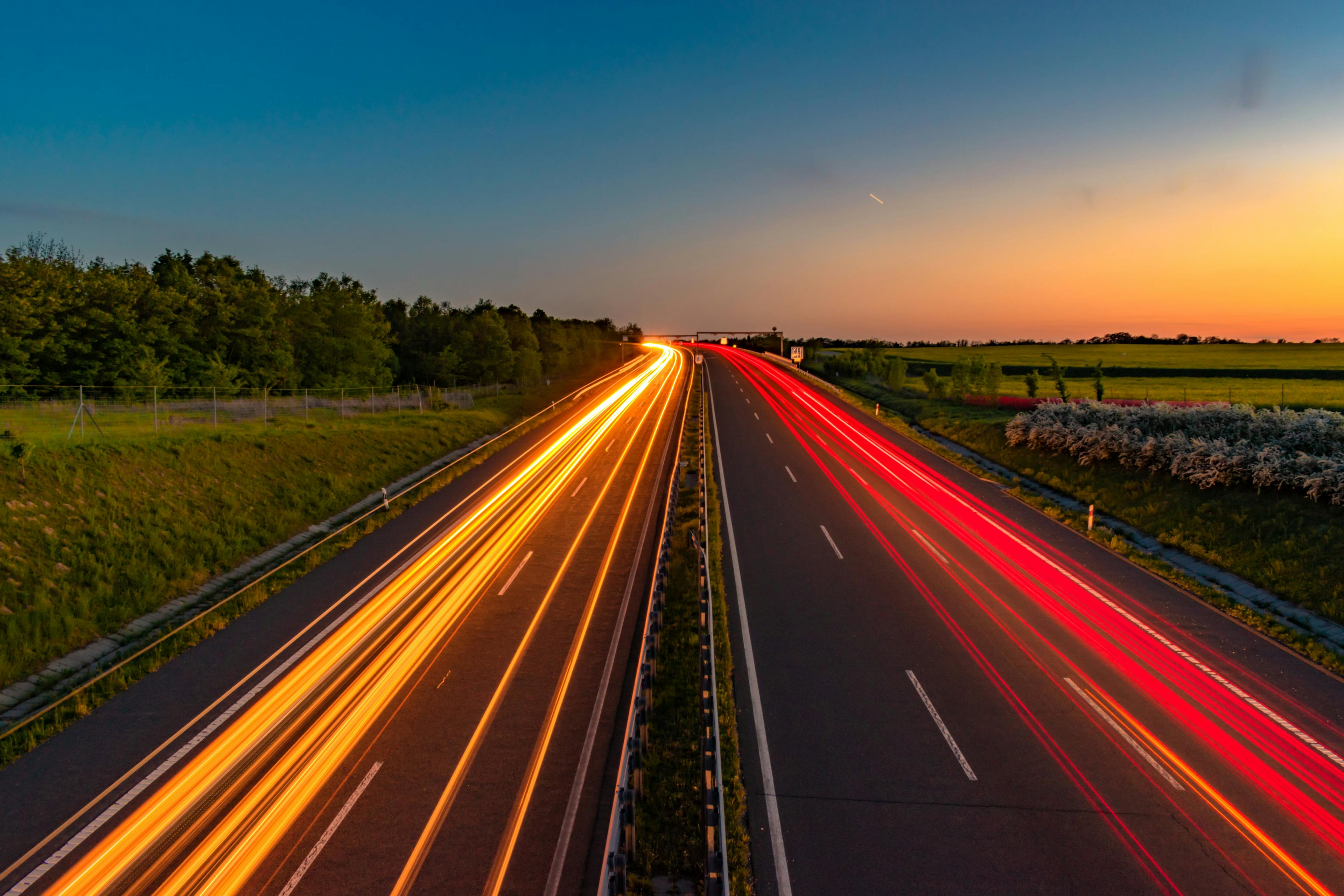 Highway at sunset with light trails from vehicle headlights and taillights