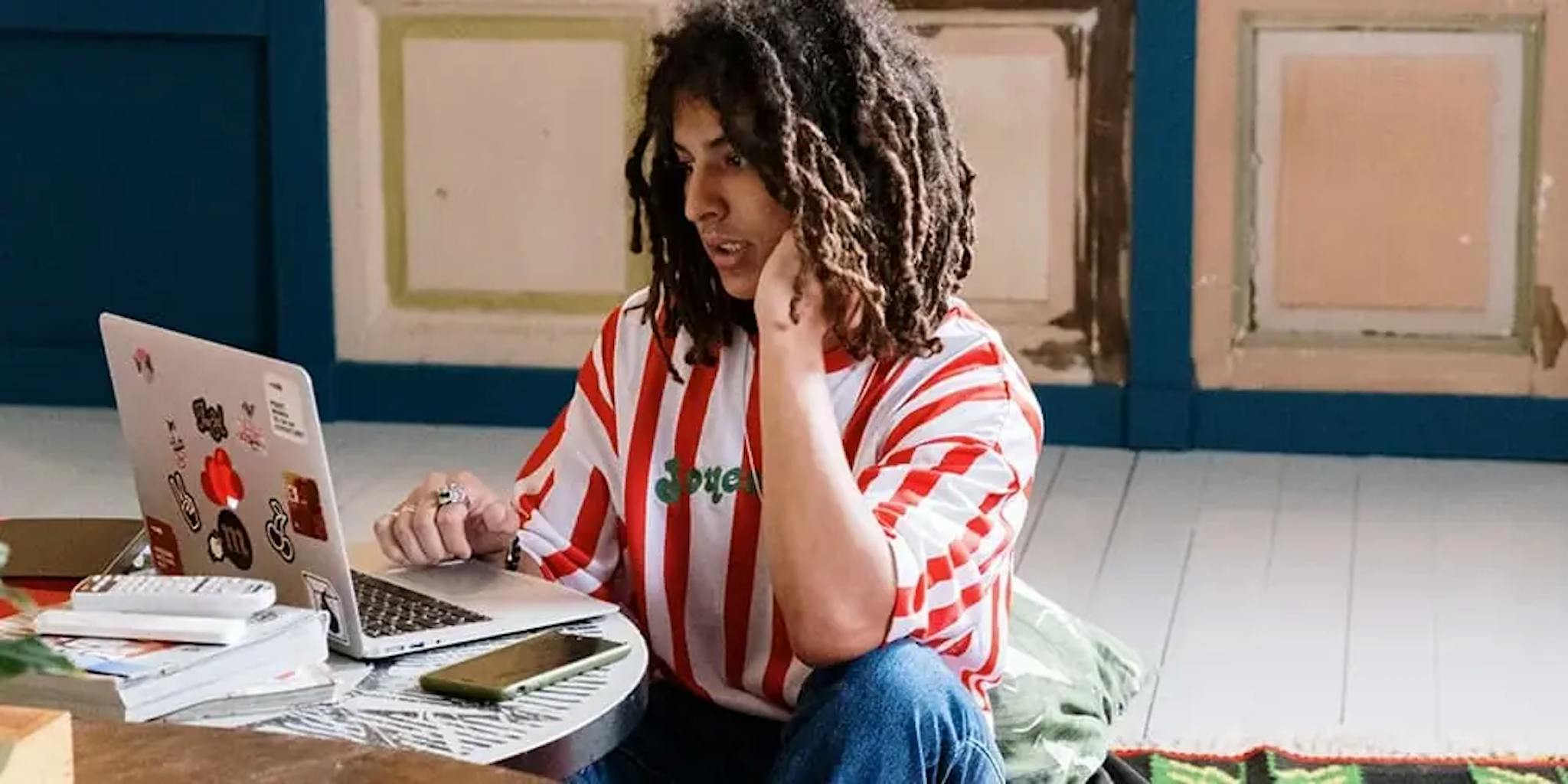 Erkek bir kişi masanın üzerinde duran dizüstü bilgisayarı kullanıyor.