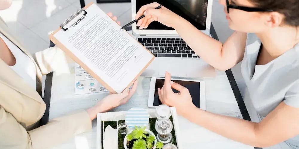 Bir kağıt belge üzerinde çalışan iki kadın