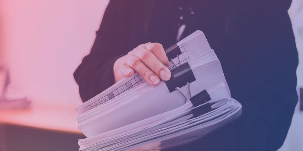 Elinde kırpılmış kağıt destesi tutan bir kişi.