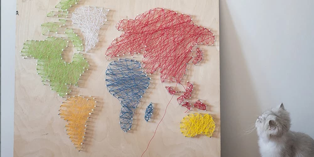 Yavru kedi bir parça ip sanatının yanında yerde konumlandırılmıştır