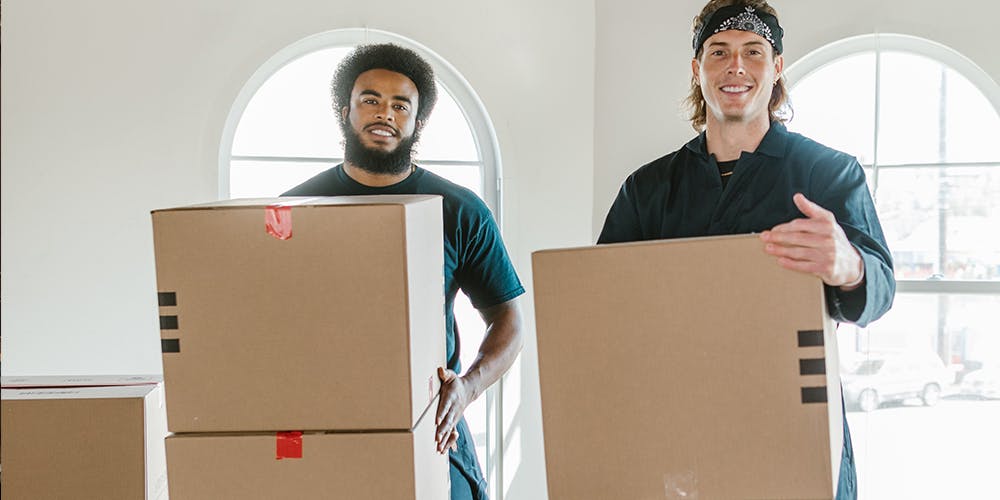 Kargo kutularını taşıyan iki kişi