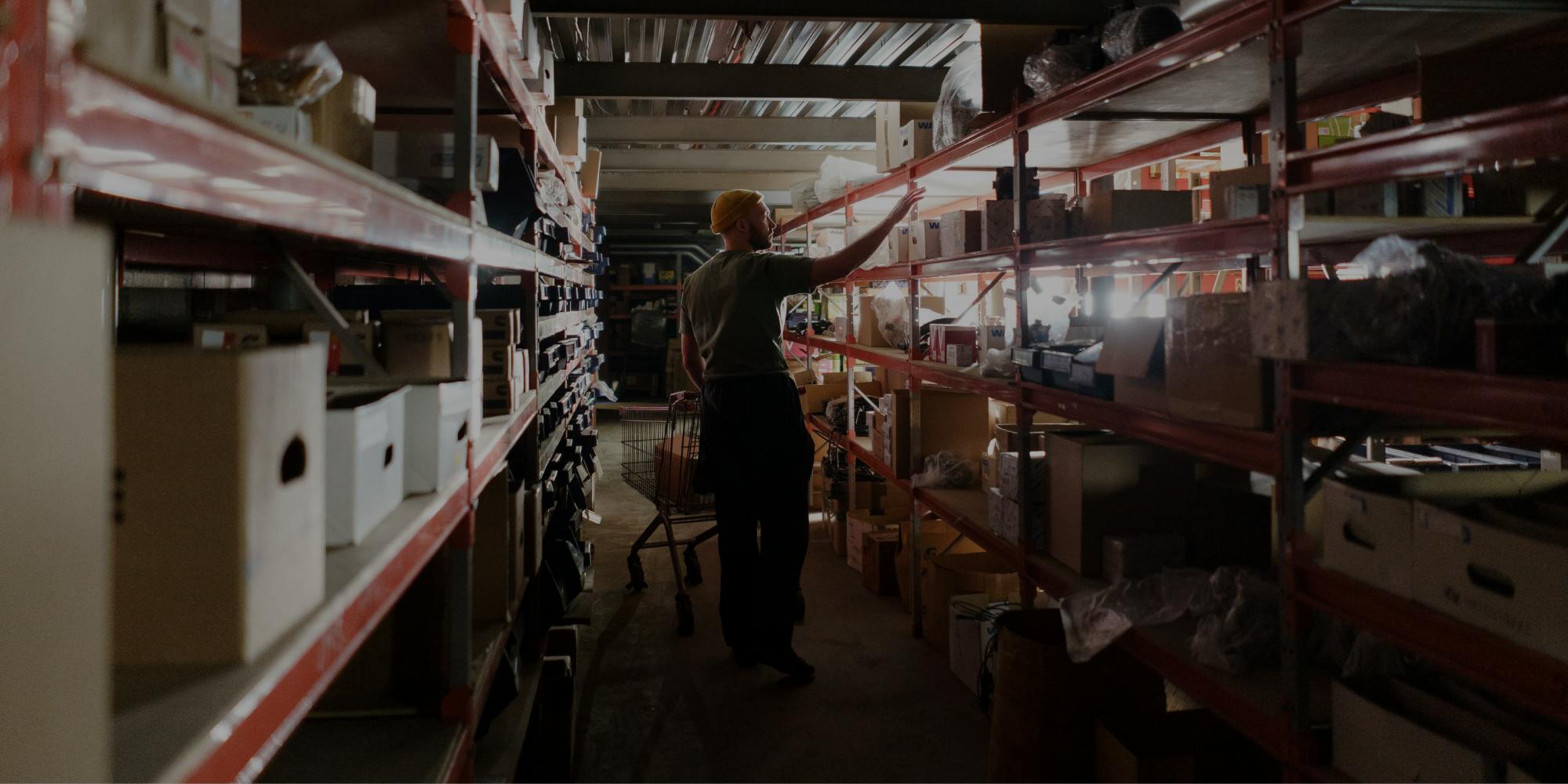 Warehouse worker checking inventory on shelves with boxes and products