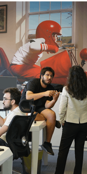 OPLOG team members having a discussion in office space with sports themed wall art