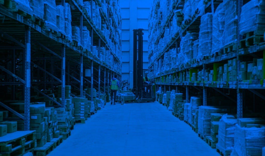 Warehouse aisle view with high storage racks in blue lighting effect