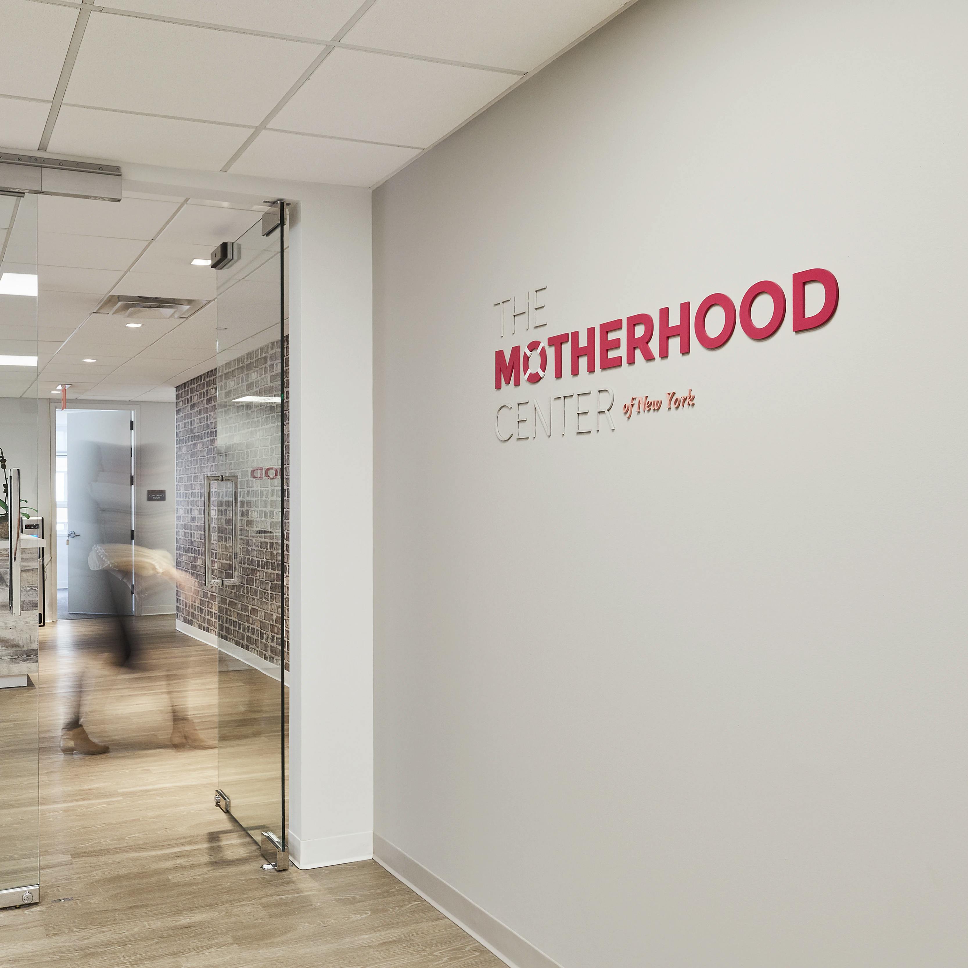 Signage of The Motherhood Center logo on a white wall at the center