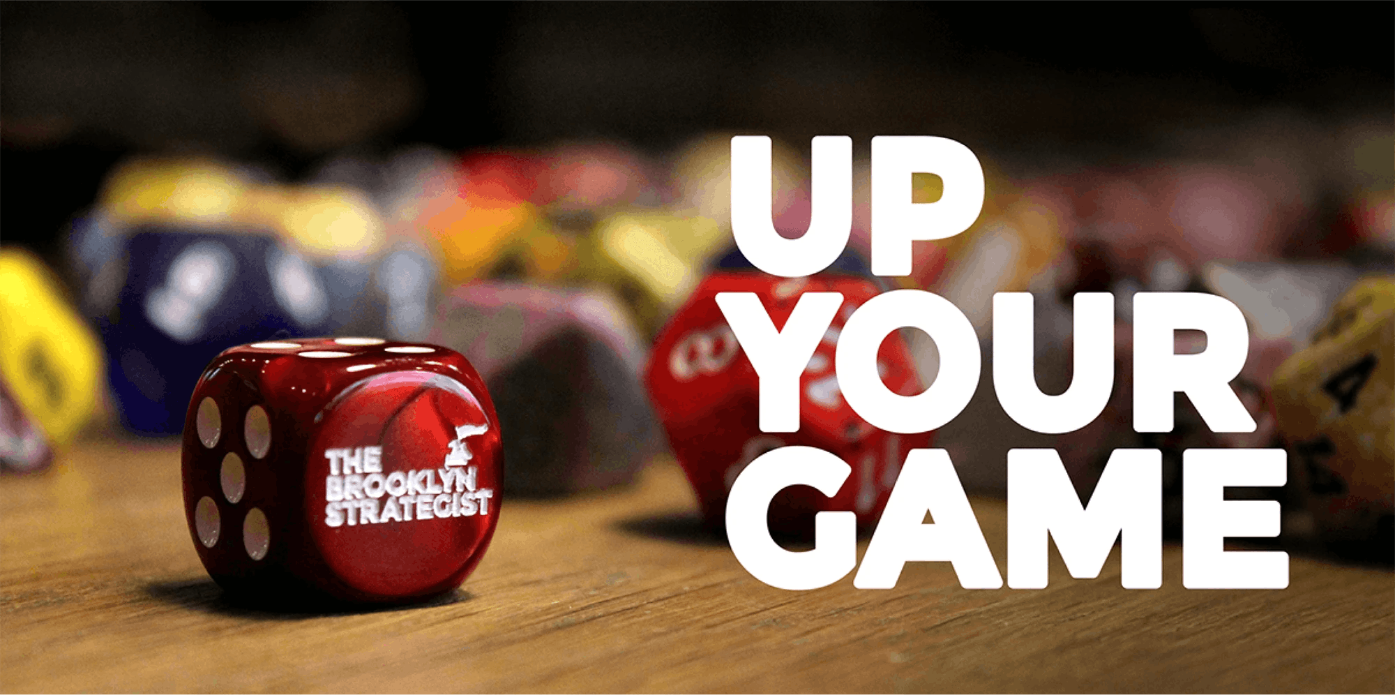 Promo image of custom dice with The Brooklyn Strategist logo and "Up Your Game"