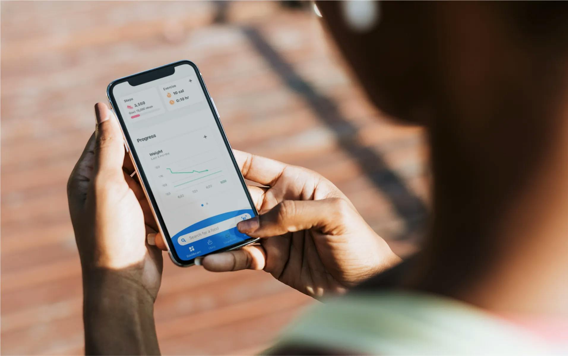 Close up of a person holding a phone and looking at the MyFitnessPal app dashboard
