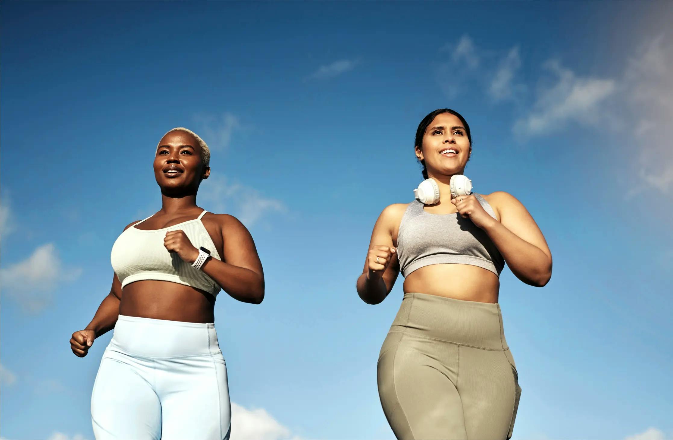 Two women running against a blue sky