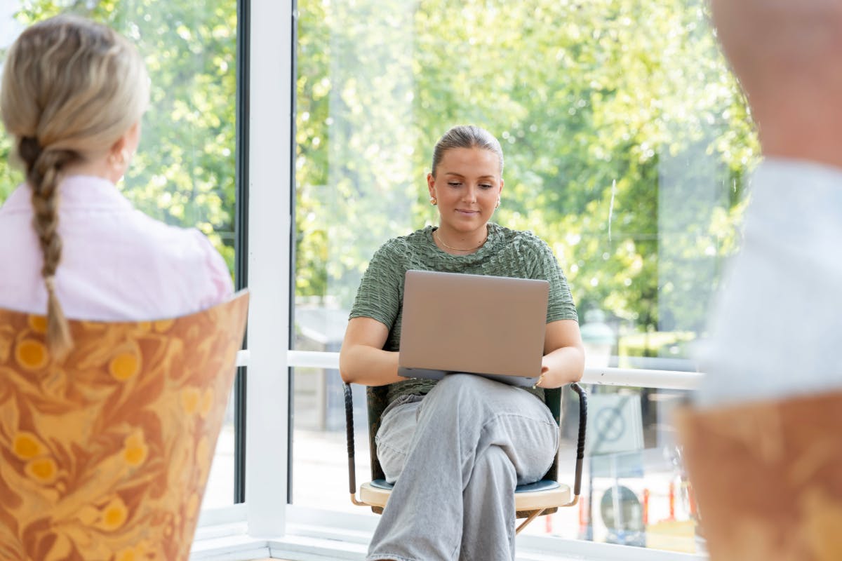 Student working on a laptop beside a window