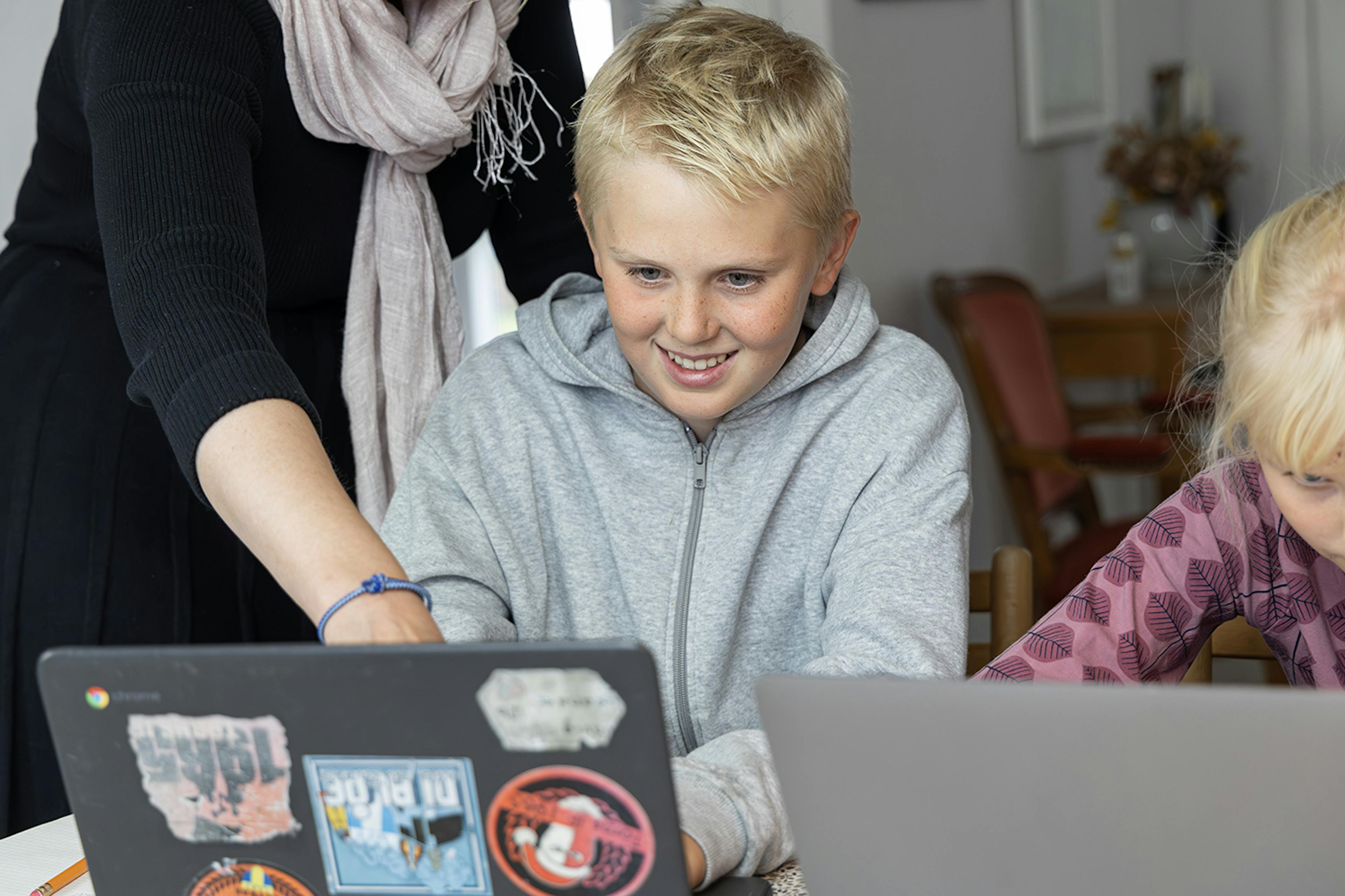 Young Student using laptop with help from teacher