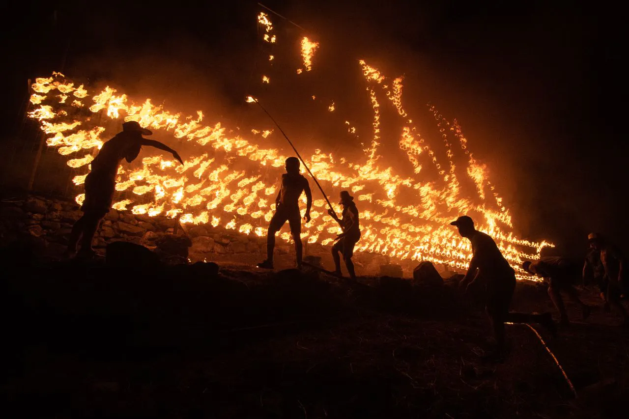 Men lighting fires on the side of a mountain
