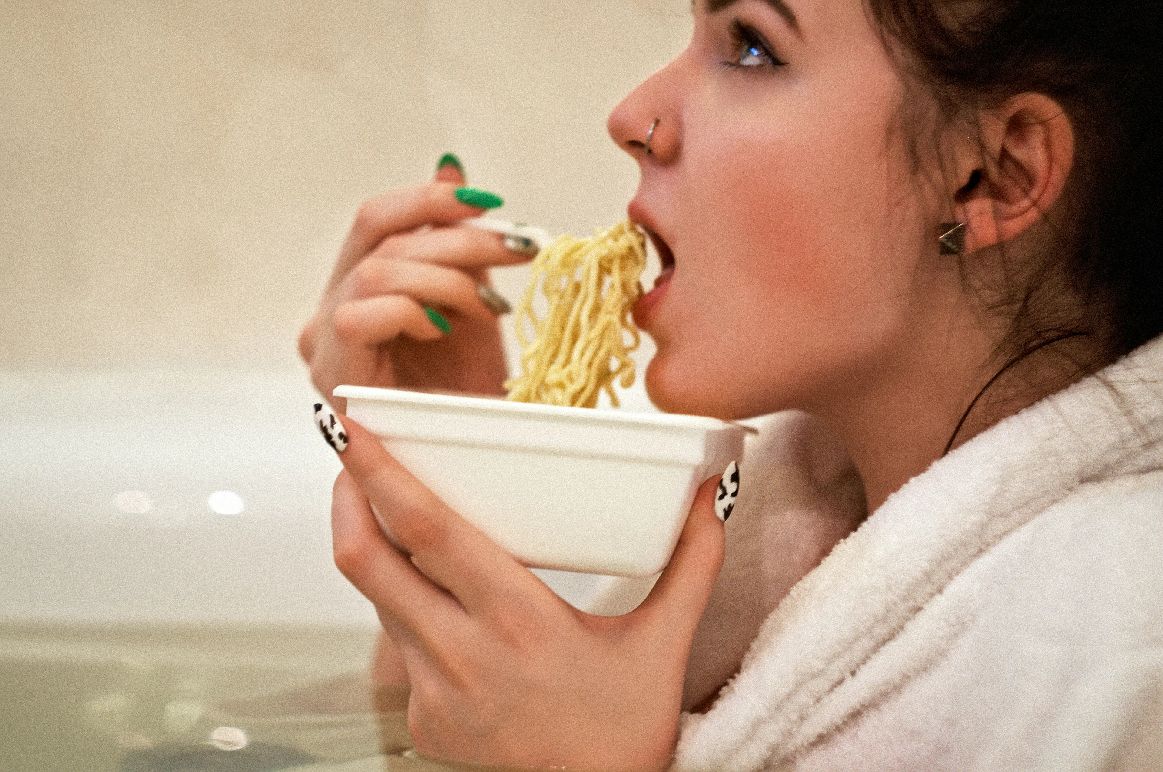 A lady eating a bowl of noodles
