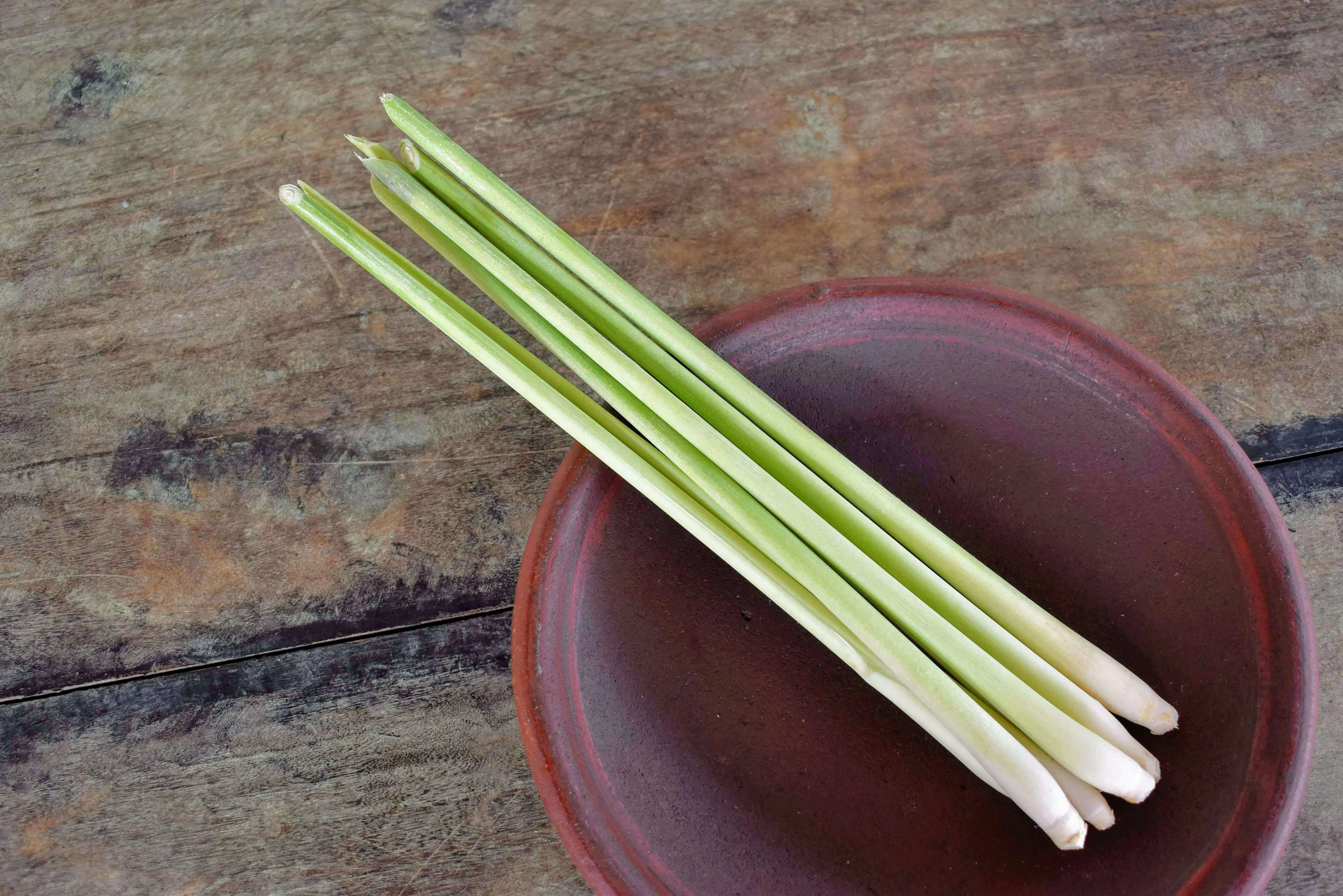 Lemongrass in a brown bowl on a wooden table.