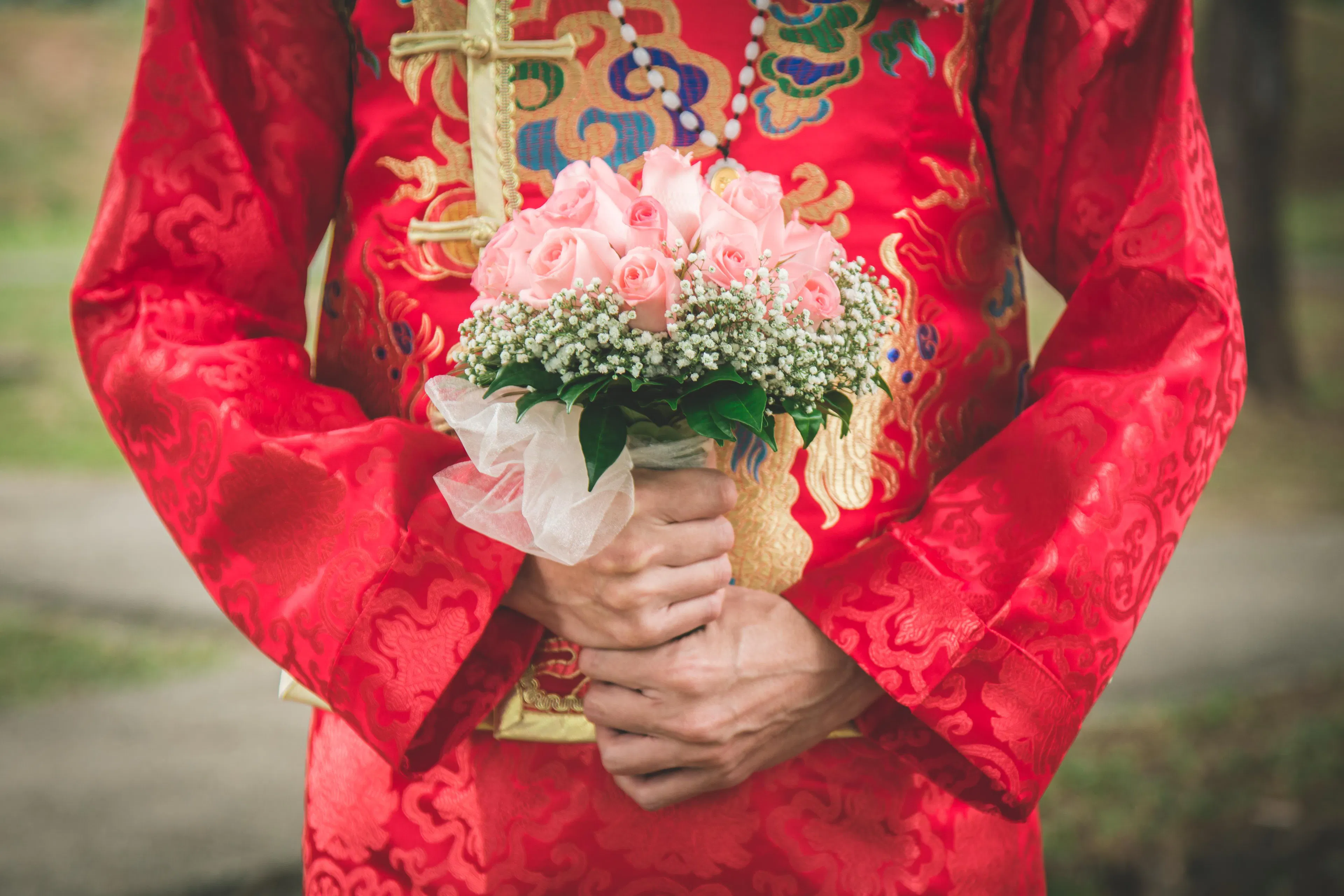 A lady holding a bouquet and wearing a traditional Chinese wedding dress