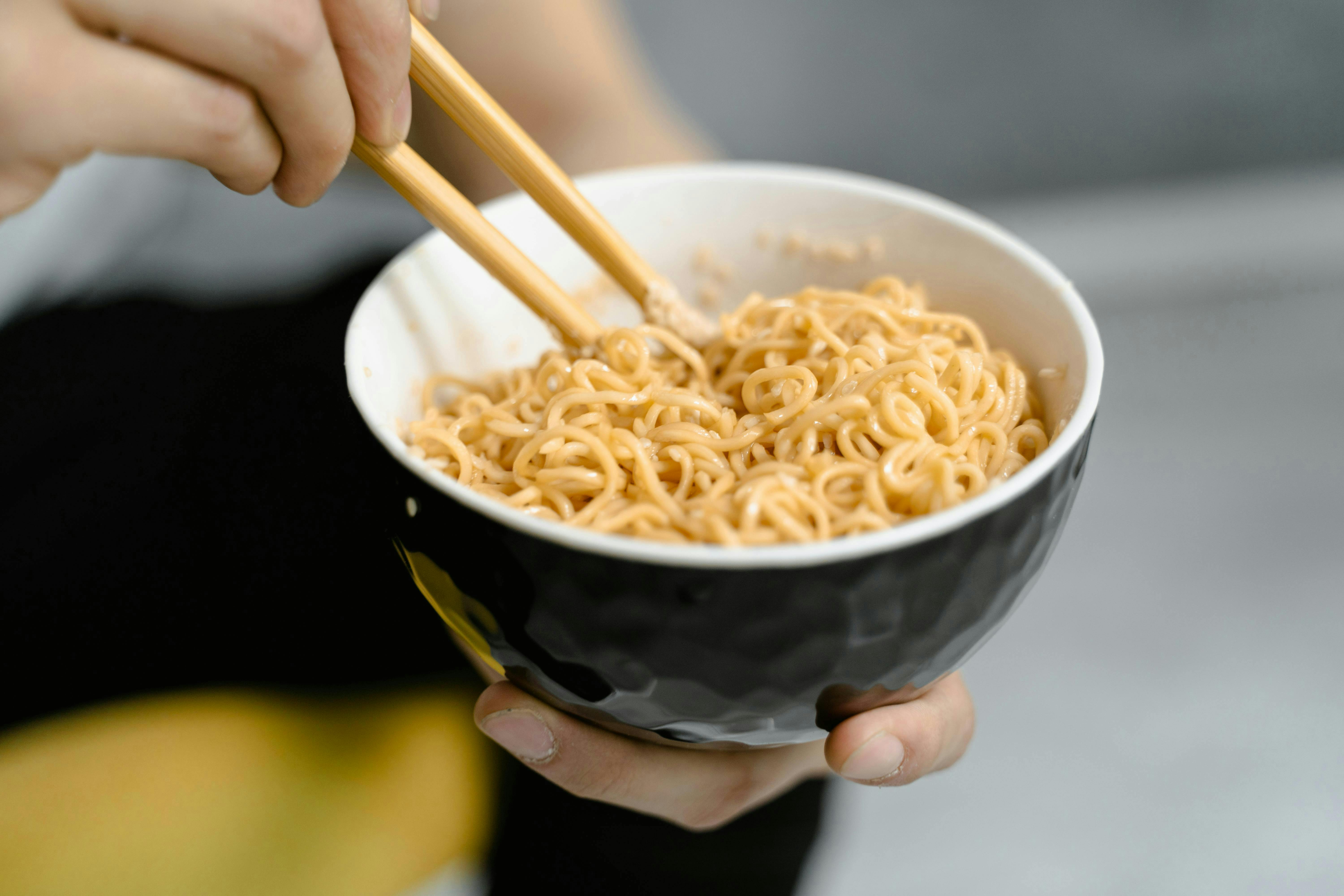 Someone holding a bowl of instant noodles with chopsticks