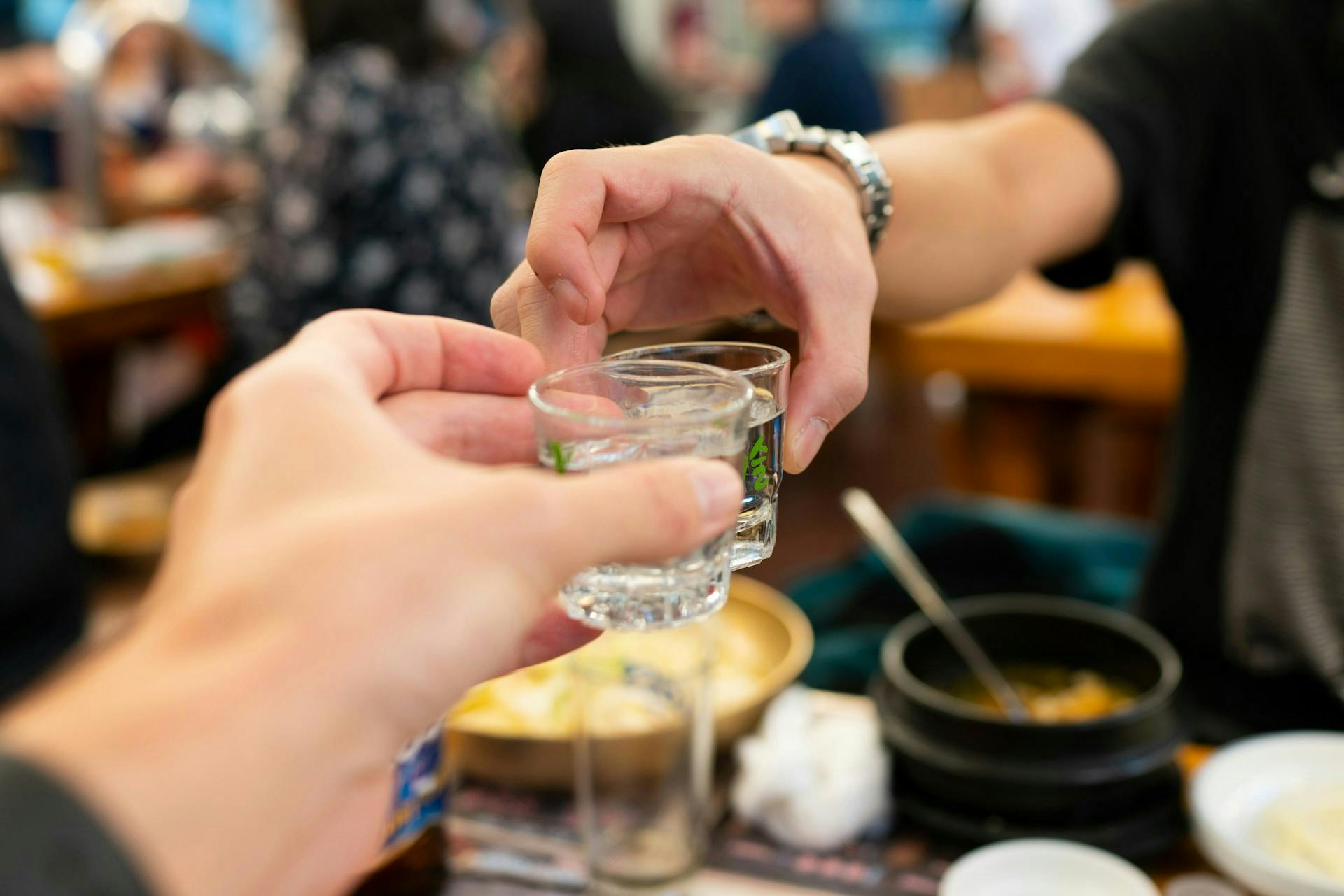 Korean people enjoying shots of soju during a meal