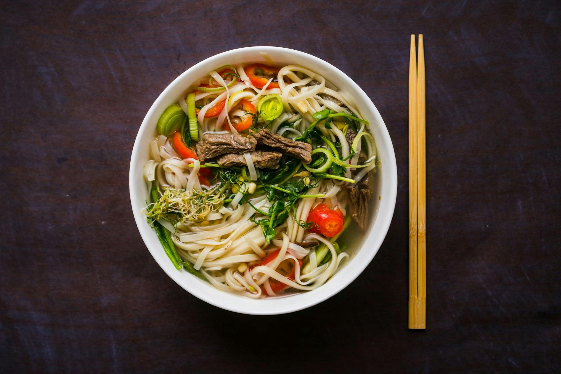 Noodles in broth topped with beef and vegetables