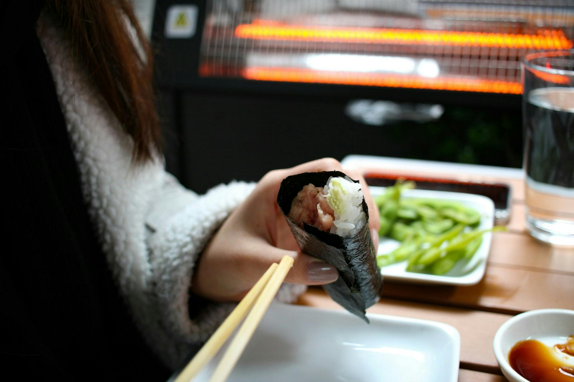 Someone eating a sushi roll wrapped in a nori seaweed sheet