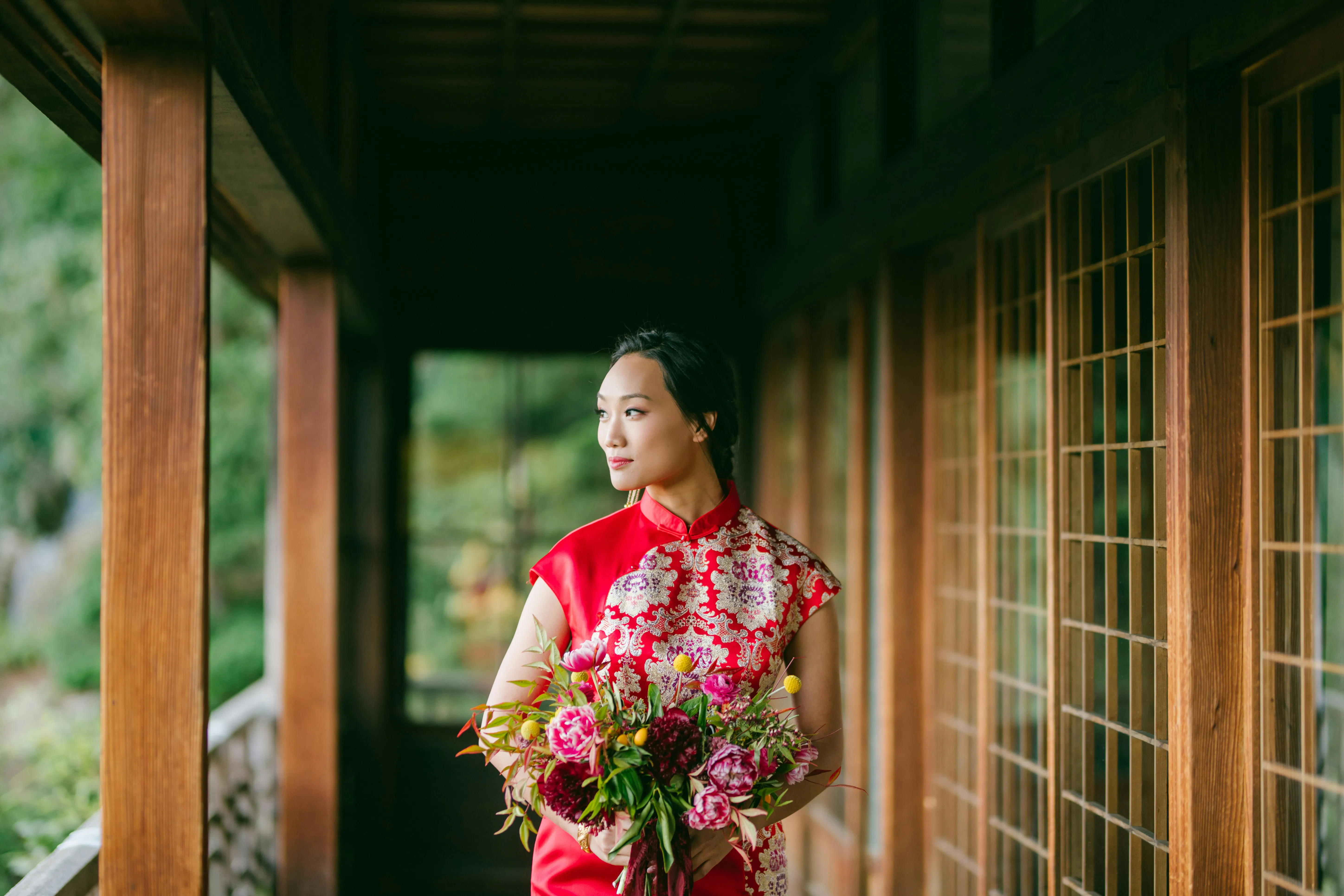 A bride at a Chinese wedding wearing a red dress and holding a bunch of flowers