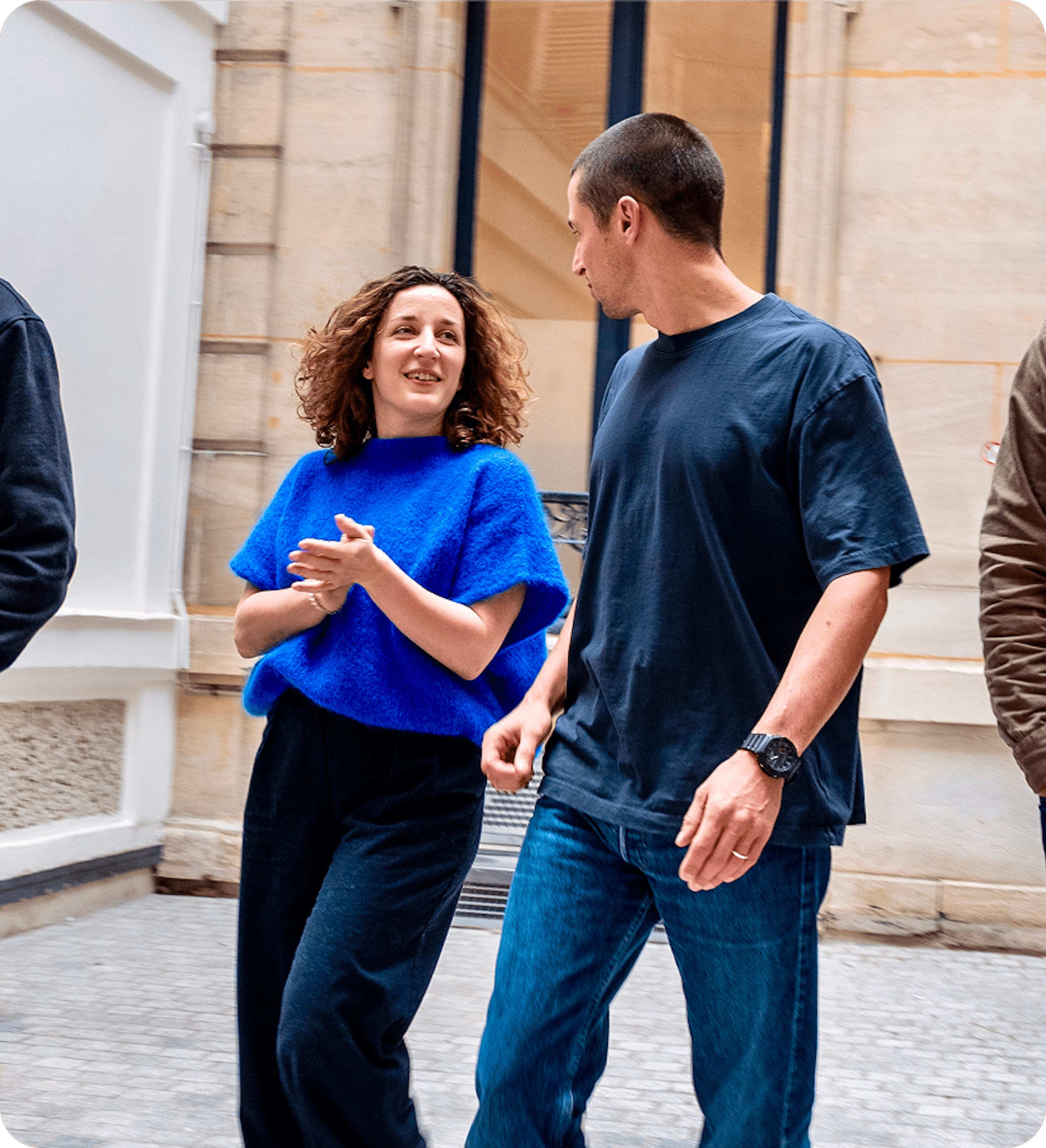 Deux personnes discutent en marchant dans une cour urbaine.
