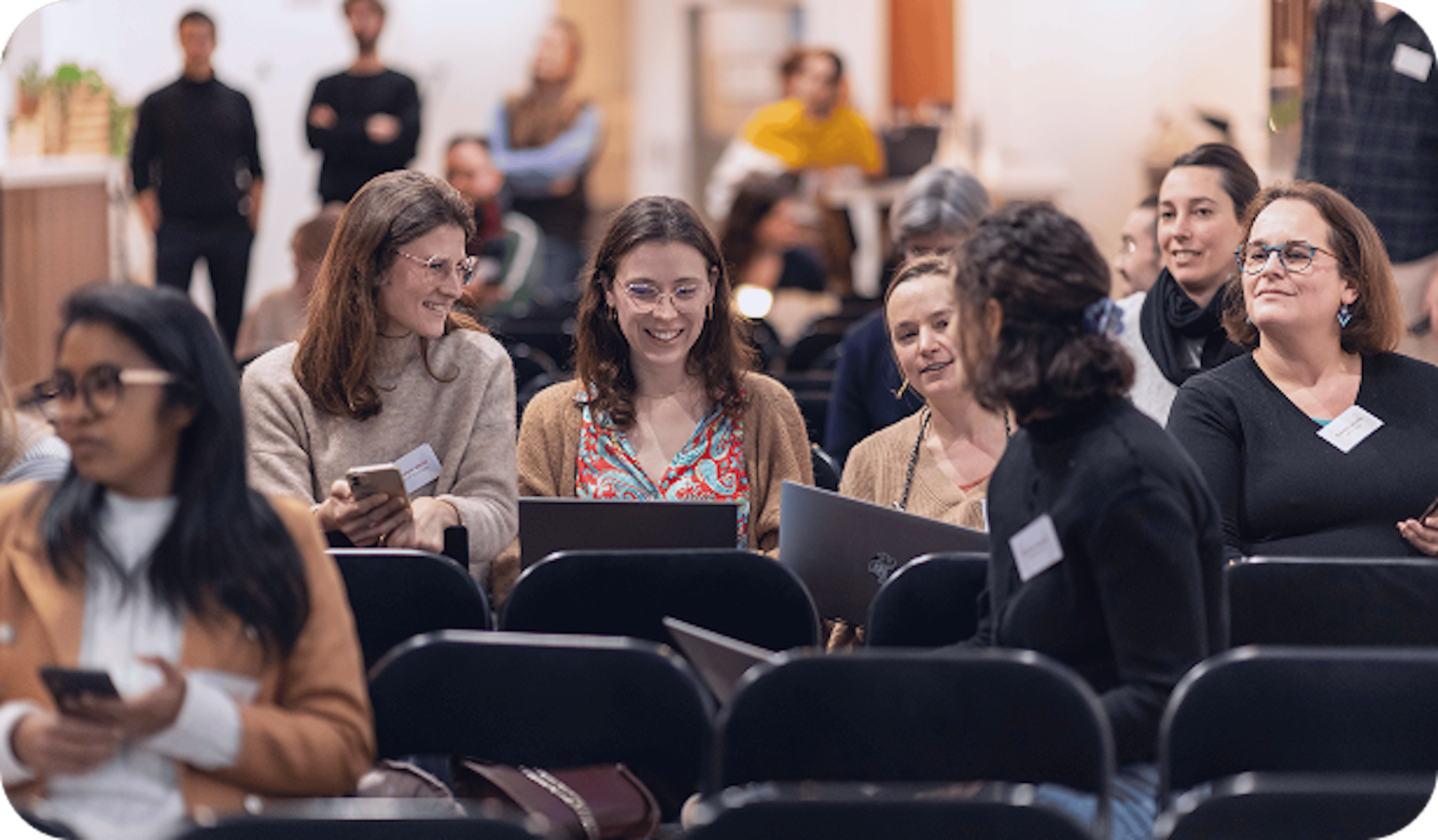 Groupe de participants assis, certains utilisant des ordinateurs, pendant une session