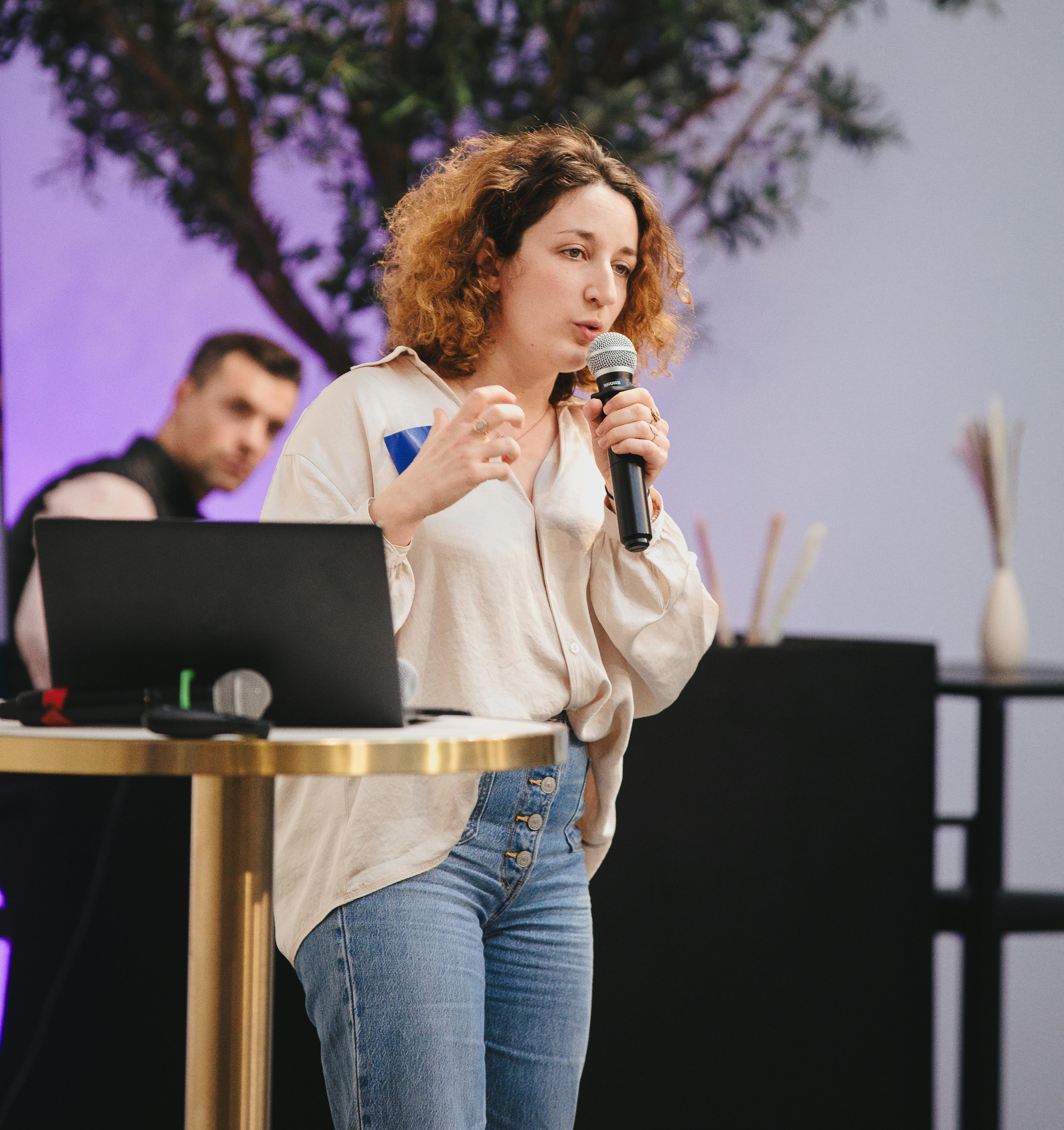 Intervenante présentant un sujet au micro devant un public.