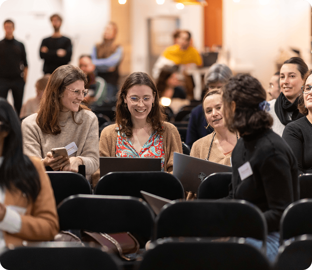 Participants échangeant avant une conférence, ordinateurs portables ouverts.