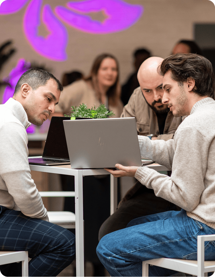 Trois personnes collaborent autour d’ordinateurs portables dans un espace de travail moderne.