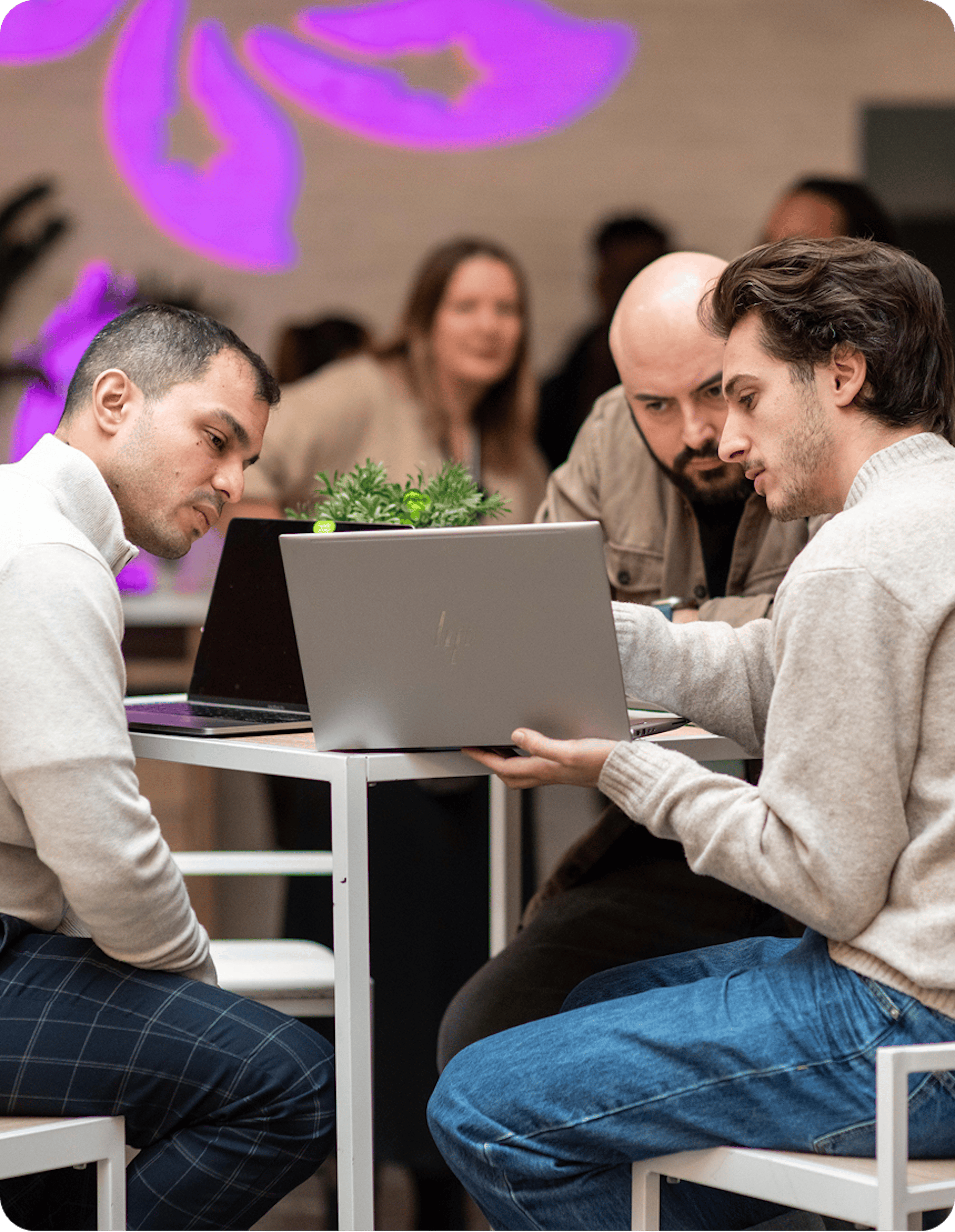 Trois personnes collaborent autour d’ordinateurs portables dans un espace de travail moderne.