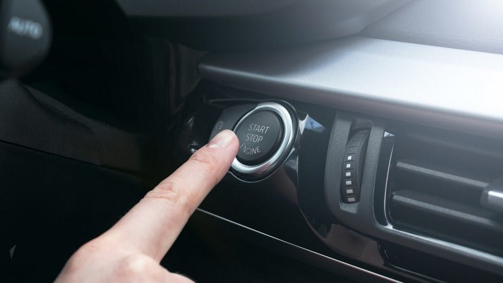 Conducteur appuyant sur un bouton de stop & start