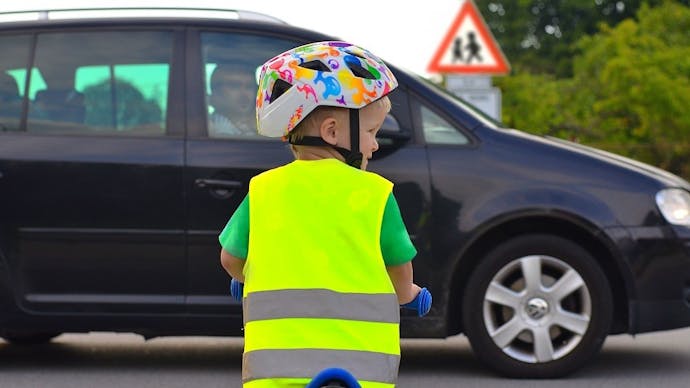 Enfant s'appretant a traverser devant un panneau de danger de traversee d'enfants