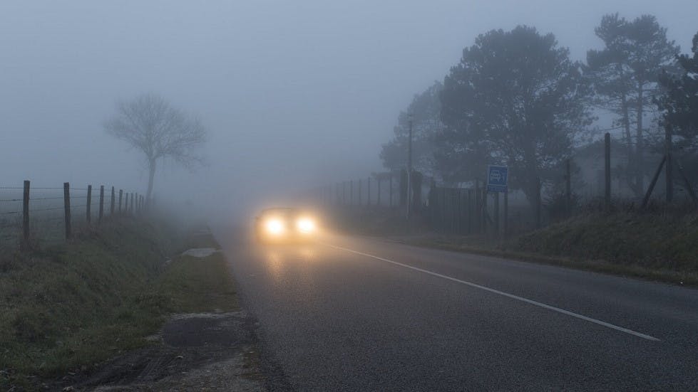 Feux d'une automobile circulant de nuit sous le brouillard