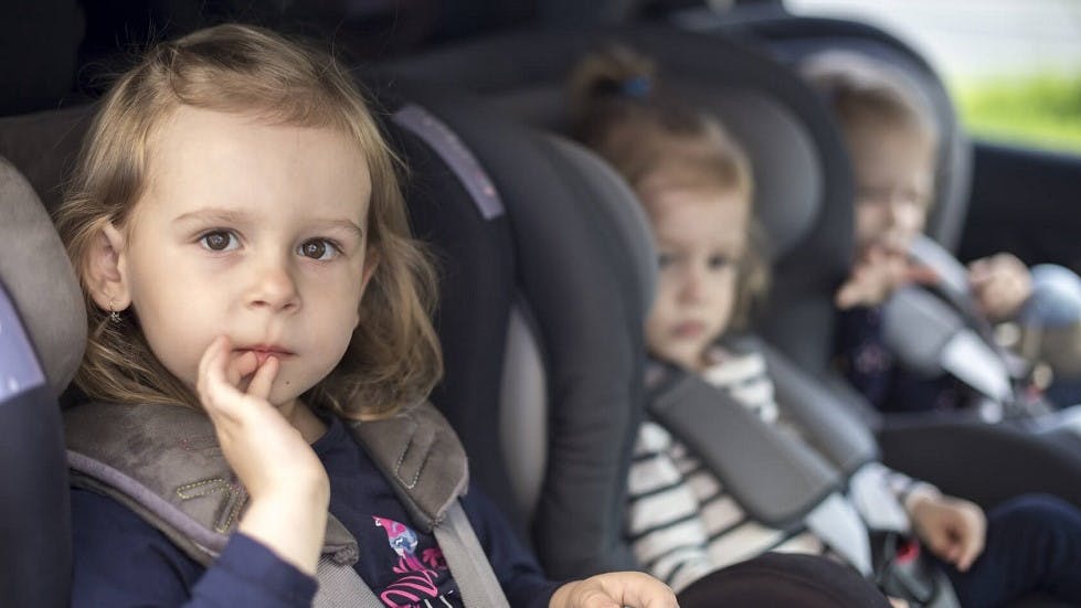 Petites filles installees dans des sieges auto a l'arriere d'une voiture