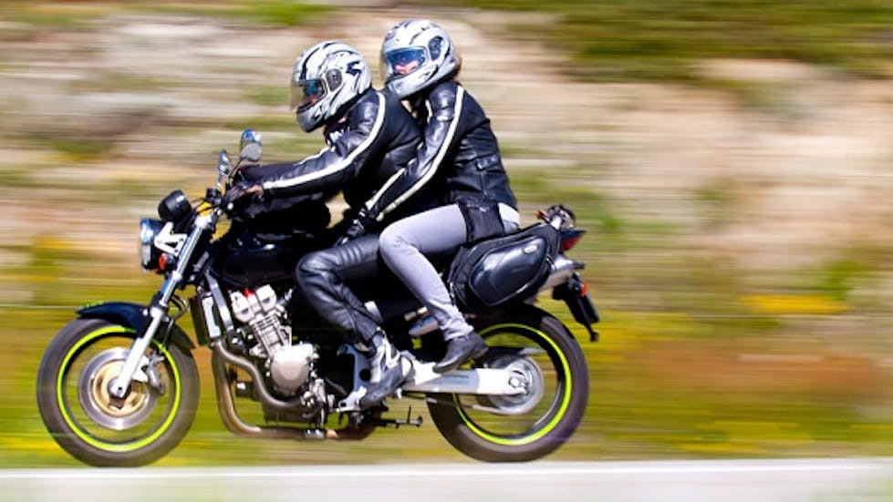 moto roulant vite avec un passager à l'arrière